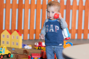 A young boy playing with a toy telephone