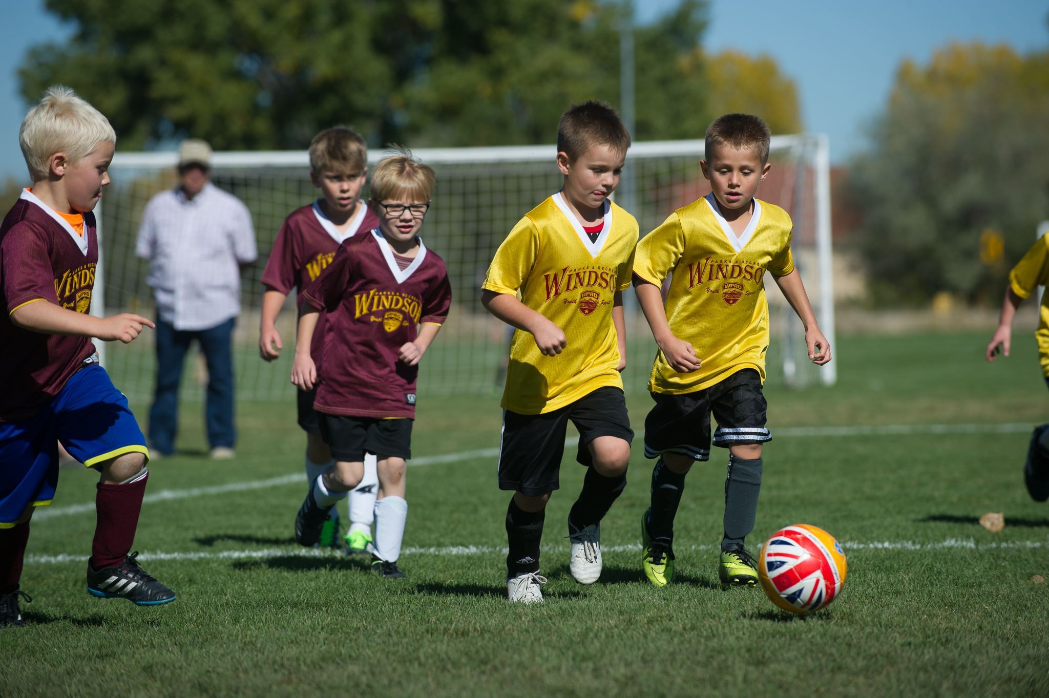 Young children playing soccer on an outdoor grassy field
