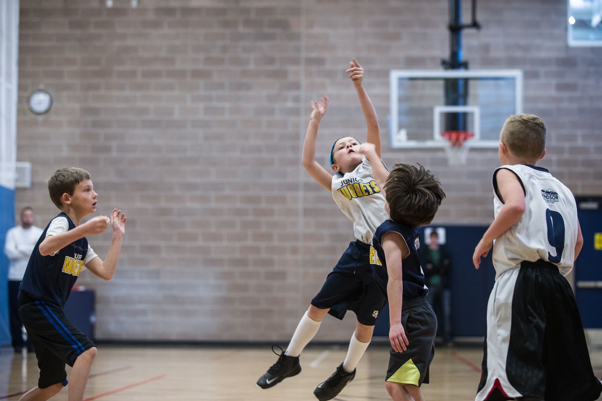 A group of young boys playing basketball in an indoor facility