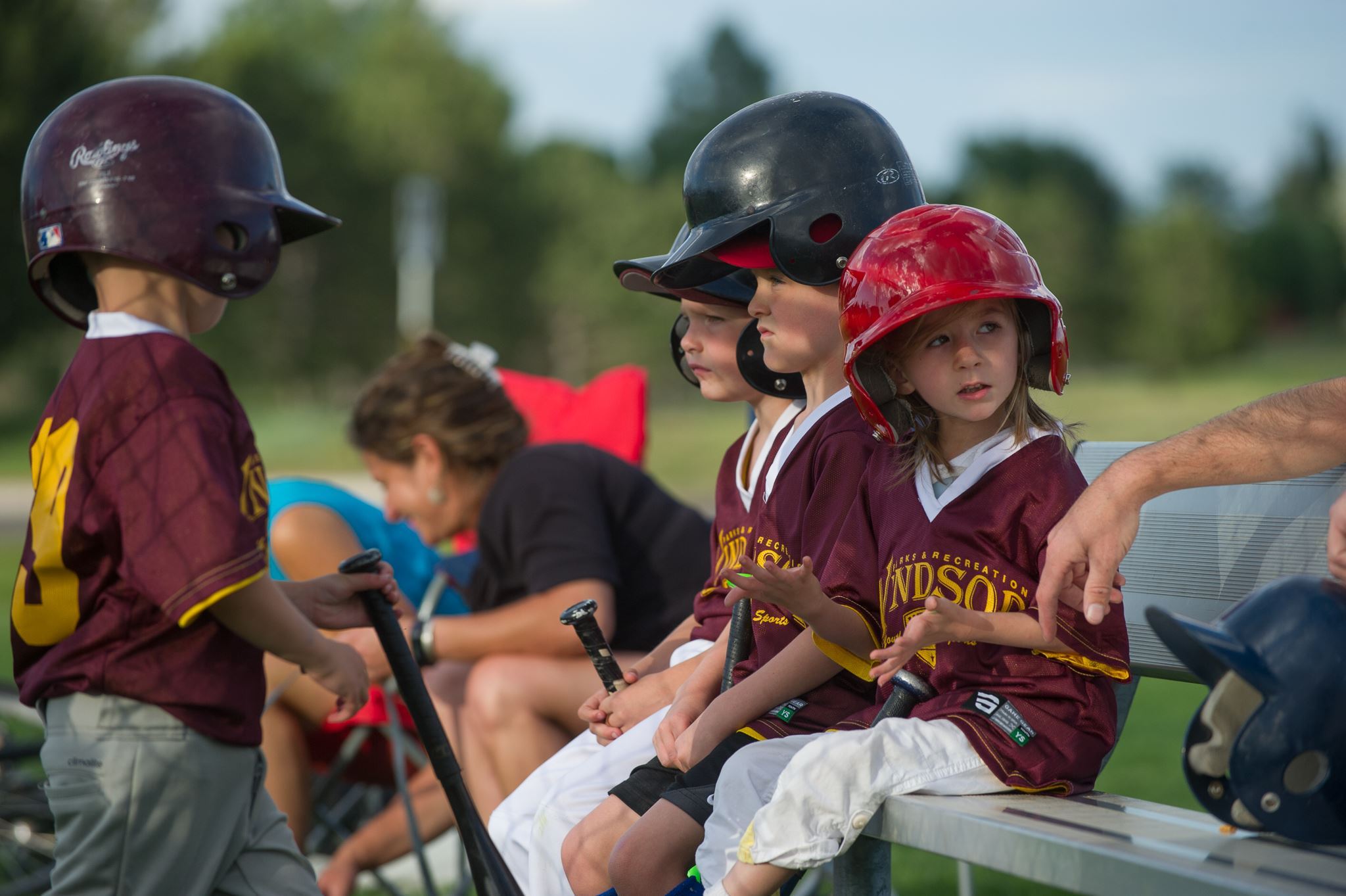 Kids Sitting on Bench with Batting Helmets On