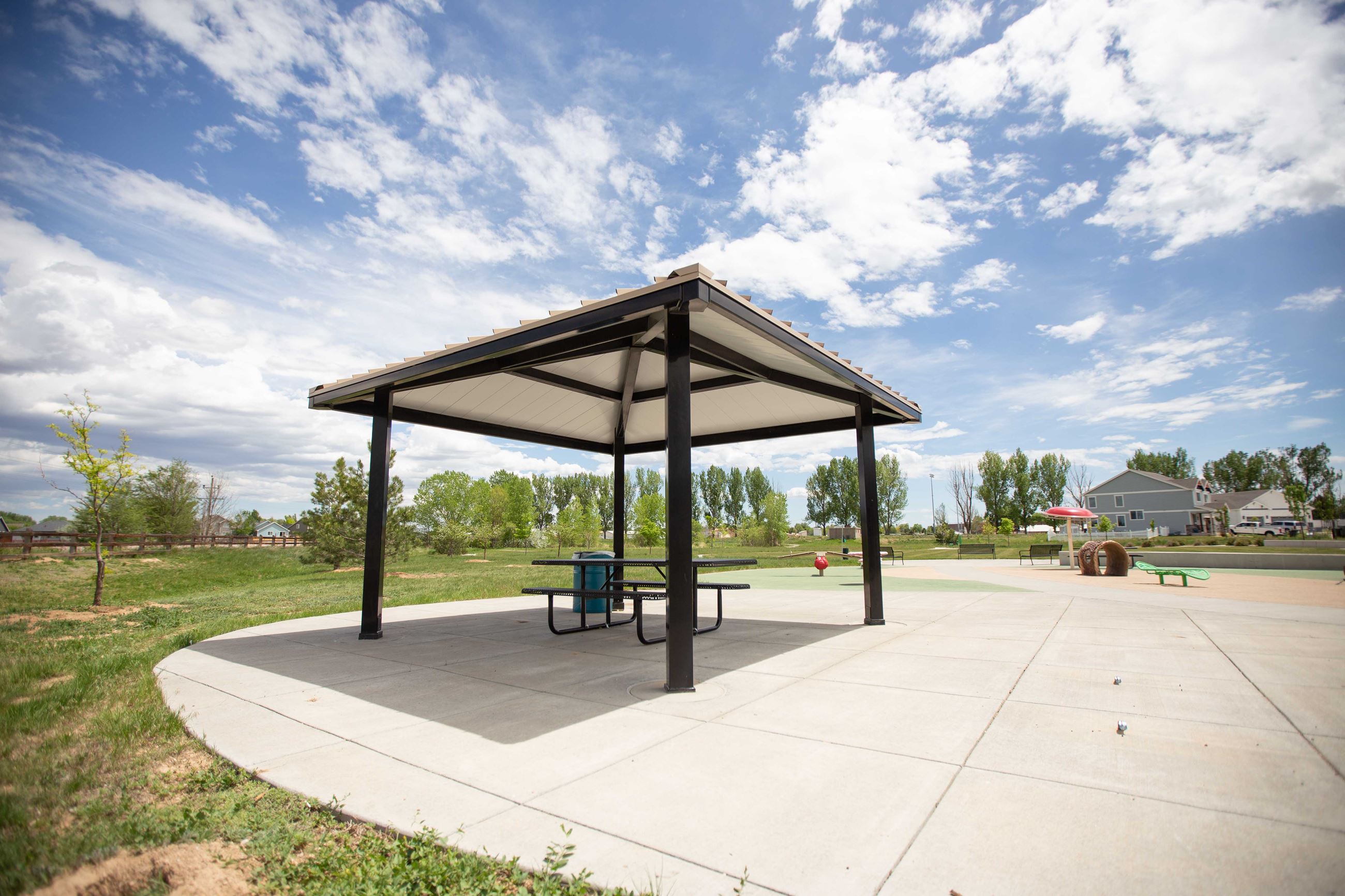 Park Shelter with picnic table underneith and playground in background