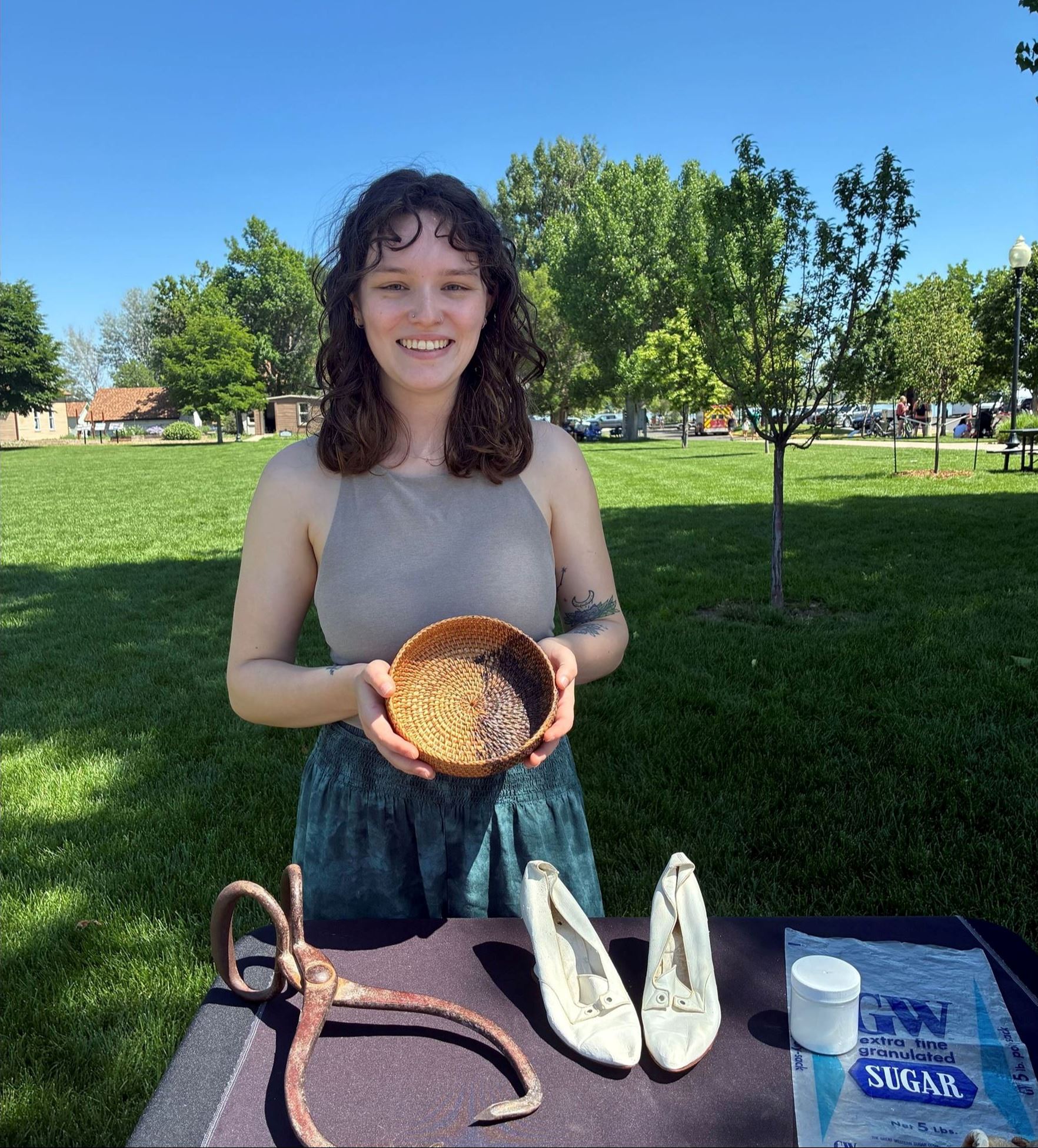 Color photograph of a girl standing at a booth holding a woven basket.