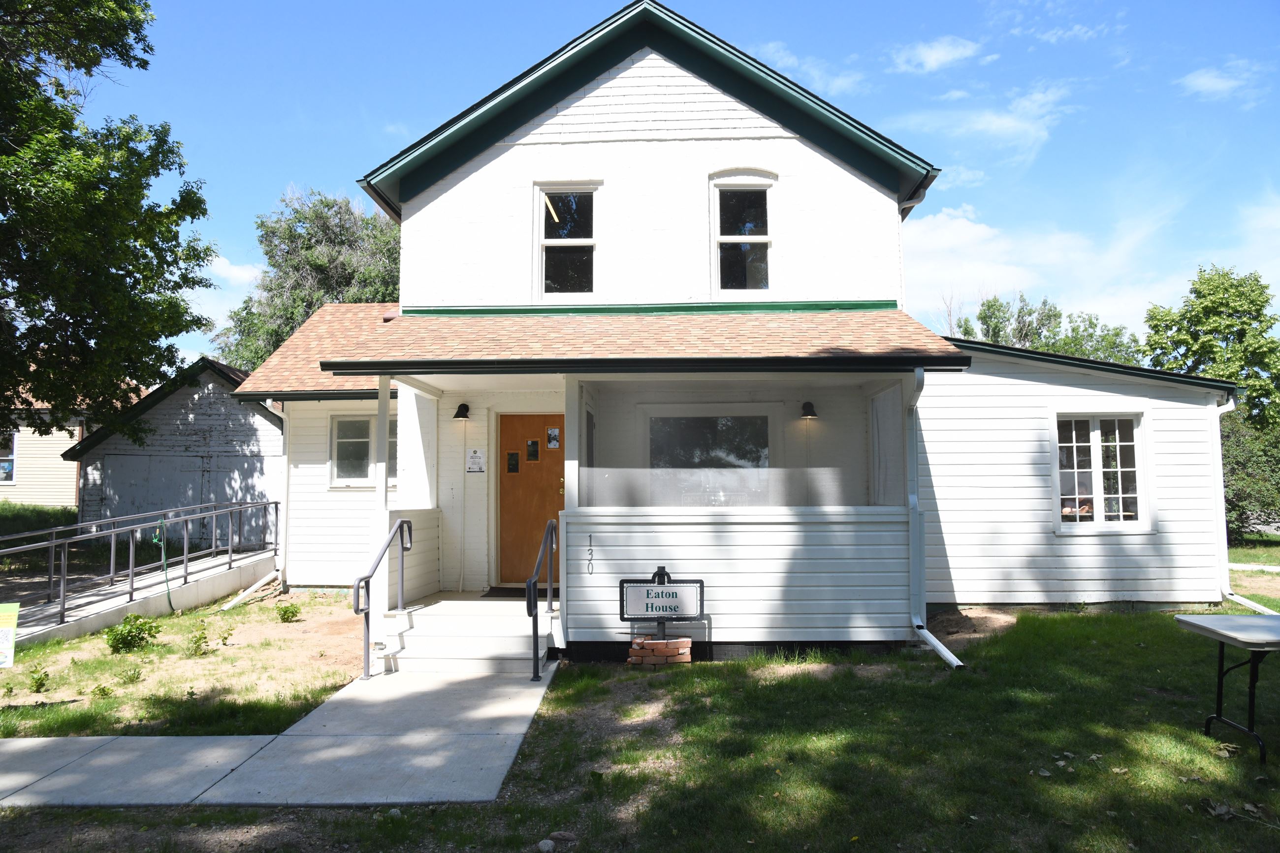 Color photograph of the front of a white, brick, two story house.
