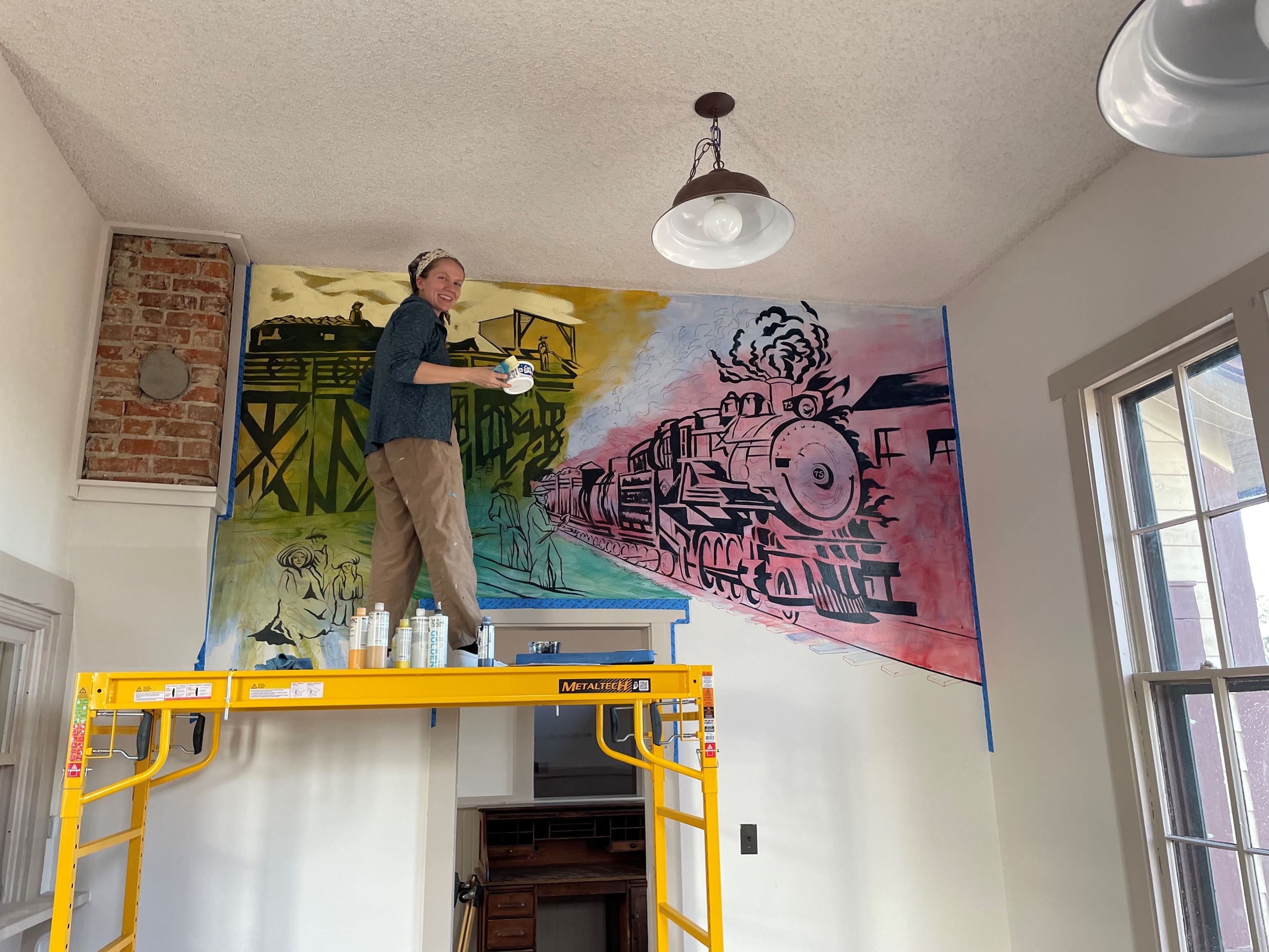 Color photograph of a person painting a mural.